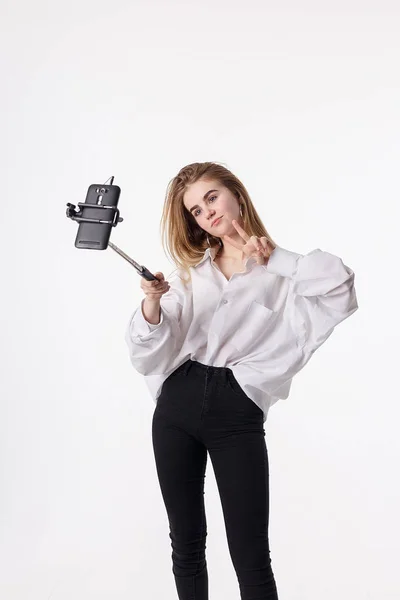 Ung söt flicka gör själv porträtt med smartphone ansluten till selfie stick — Stockfoto