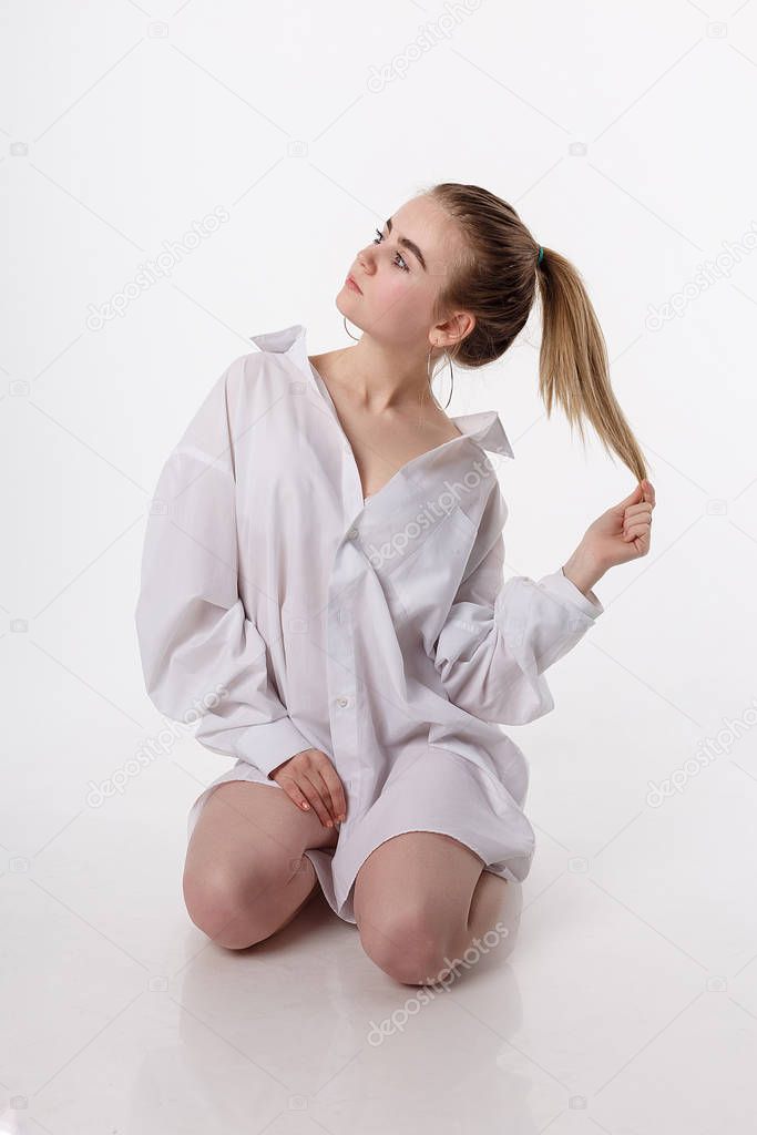 young female sitting on floor on knees. pretty girl with long hair in studio