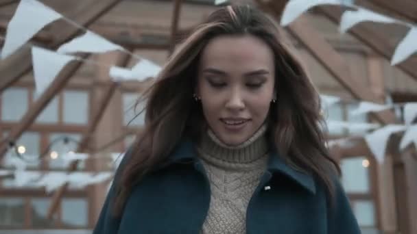 Stijlvol jong aziatisch mooi meisje in blauwe jas, coltrui met golvend haar glimlacht — Stockvideo