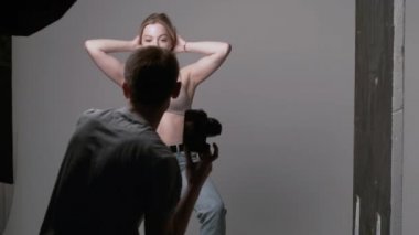 Sahne arkasında erkek fotoğrafçı seksi beyaz kadın pozu veriyor.