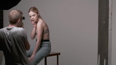 Sahne arkasında erkek fotoğrafçı seksi beyaz kadın pozu veriyor.