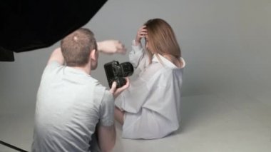 Sahne arkasında beyaz kız pozu veren erkek fotoğrafçı.