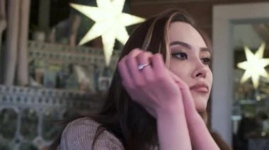 şık, genç, düşünceli Asyalı, uzun saçlı, bej kumaşlı güzel kız.