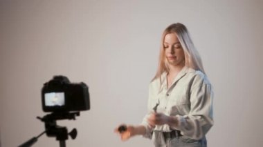 Makyaj hakkında video kaydeden genç bir kız fotoğraf makinesiyle tripoda bağlanmış.