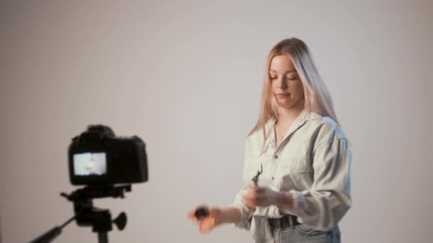Menina jovem gravação de vídeo sobre maquiagem com câmera de fotos anexada ao tripé — Vídeo de Stock