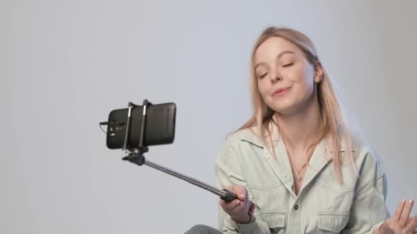 Happy female records video pro vlog s chytrým telefonem připojeným k selfie tyčce — Stock video