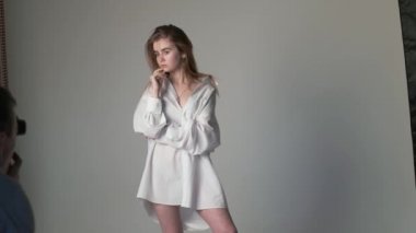 Sahne arkasında beyaz kız pozu veren erkek fotoğrafçı.