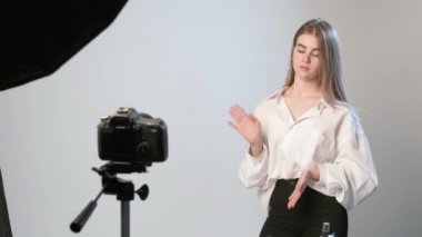 Mavi eldiven giyen bir güzellik blogcusu, kameranın önünde dikilip video kaydediyor.