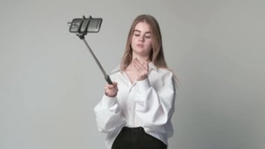 Akıllı telefonlu makyaj videosu çeken genç bir kız selfie çubuğuna bağlanmış.