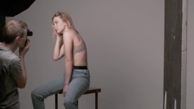 Sahne arkasında erkek fotoğrafçı seksi beyaz kadın pozu veriyor.