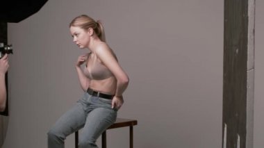 Sahne arkasında erkek fotoğrafçı seksi beyaz kadın pozu veriyor.