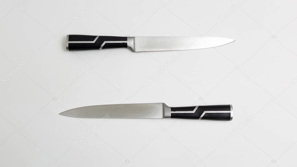 two sharp kitchen knives with black handles. white background flatlay. Top view