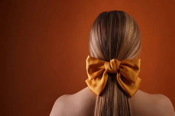 Menina com arco no cabelo, visão traseira. nua feminino de volta no fundo laranja — Fotografia de Stock