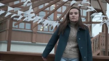 stylish asian pretty girl in blue coat and turtleneck looking at camera outdoors