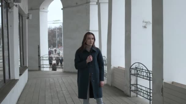 Asian pretty girl in blue coat stands alone on veranda with white stone columns — Stok video