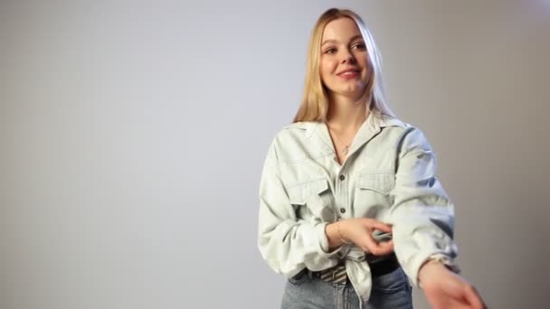 Young caucasian pretty girl with long blonde hair, smiles on white background — Stock Video