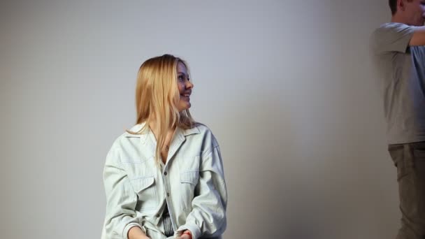 Attractive female sitting on chair while photographer setting light on stand — Stock Video