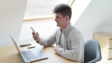 Gülümseyen adam ofisteki cep telefonundan sohbet ediyor. ev konsepti