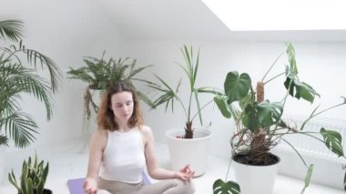 Spor kıyafetleri giyen bir kız Lotus pozisyonunda oturur. Gözleri kapalı, meditasyondan zevk alır.