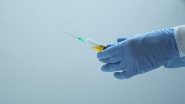 Arts met handschoenen bereidt een vaccin voor injectie voor. spuit met gele vloeistof — Stockvideo