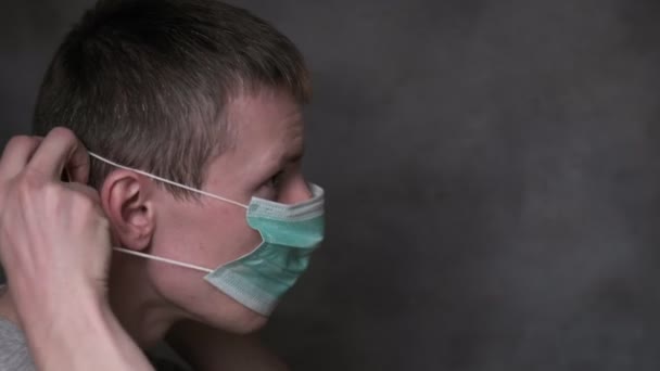 Genç adam koruyucu maske takıyor ve çıkarıyor. Virüs COVID-19 pandemik koruma — Stok video