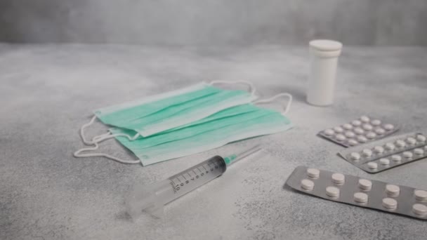 Máscaras protetoras, seringa, comprimidos de medicamentos, cápsulas, frasco para injetáveis em fundo de concreto — Vídeo de Stock