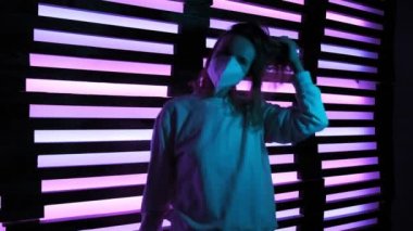 Koruyucu tıp maskeli güzel kız neon gece kulübünde dans ediyor. çılgın parti