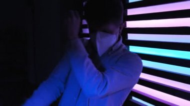Koruyucu tıp maskeli yakışıklı adam neon gece kulübünde dans ediyor. çılgın parti