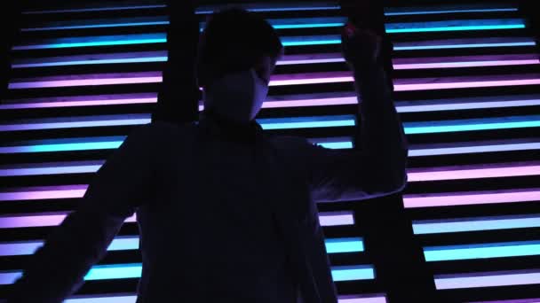 Een knappe vent met een beschermend medicijnmasker dansend in een neon nachtclub. rave partij — Stockvideo