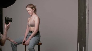 Sahne arkasında erkek fotoğrafçı seksi beyaz kadın pozu veriyor.