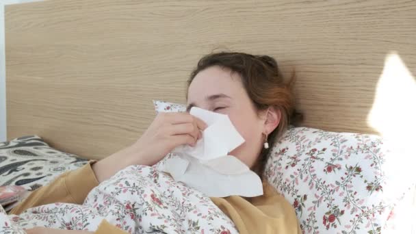 Chica enferma estornudando, sonando, limpiando la nariz con papel de seda. mujer tose en la cama — Vídeo de stock