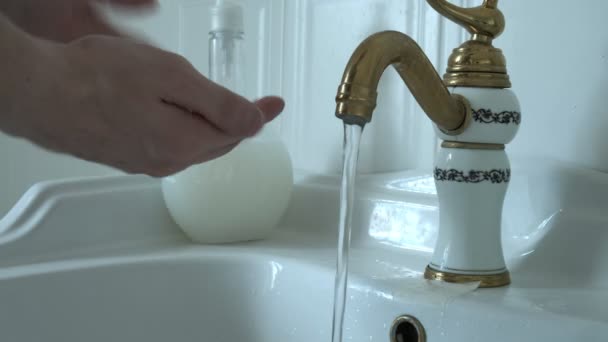Нерозпізнана біла людина миє руки з милом у раковині у білій ванній — стокове відео