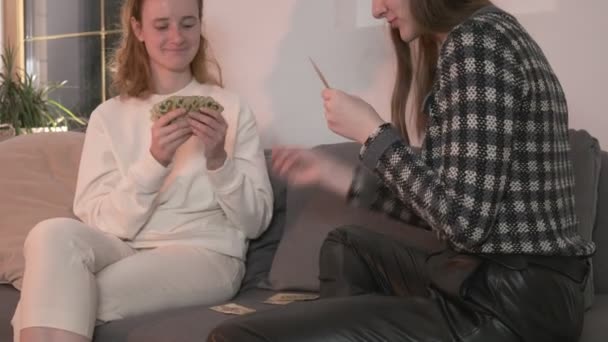 Vrienden praten, pokeren thuis, plezier hebben, lachen. meisjes kaarten op de bank — Stockvideo