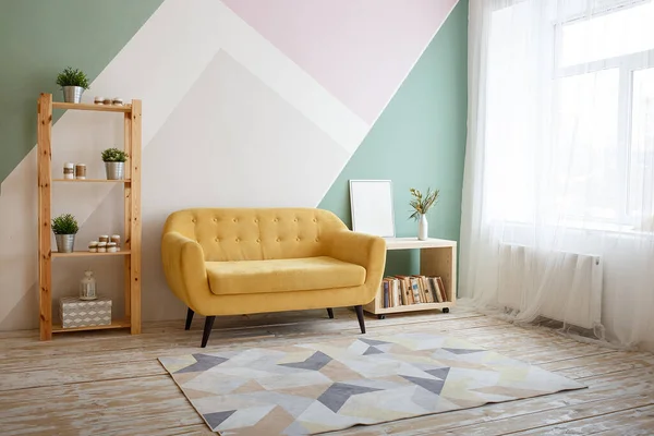 Nettes Wohnzimmer mit Couch, Teppich, grüner Pflanze auf einem Bücherregal. — Stockfoto