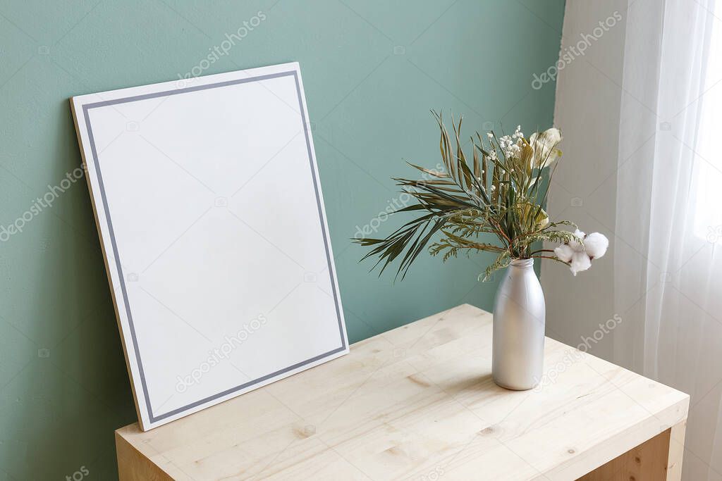 Vase with a plant on a table near a picture with copy space. Place for text. Cozy interior