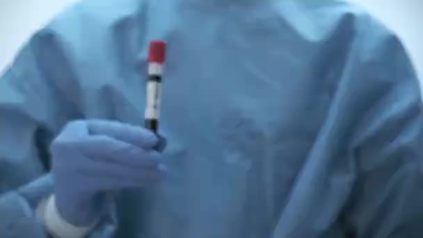 Microbiologista, assistente médico mão com luvas azuis mostrando o resultado do teste de sangue — Vídeo de Stock