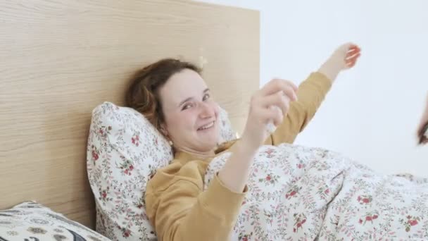 Glückliches Mädchen, das zu Hause im Bett liegt, umarmt ihre Freunde. Freunde unterstützen — Stockvideo