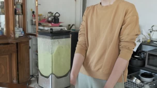 Chica joven en la cocina casera preparando batidos en licuadora. dieta de frutas saludables — Vídeo de stock