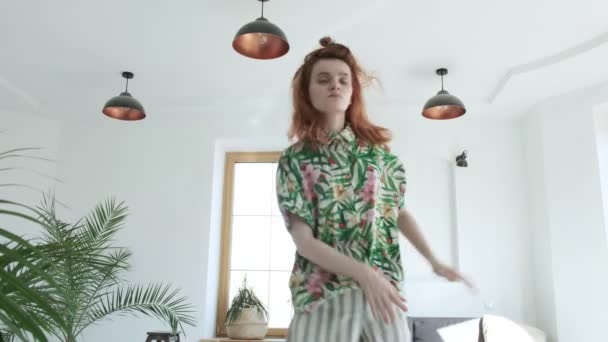 Ung lekfull flicka i blommig skjorta hoppar, larvar sig, dansar, blir galen — Stockvideo