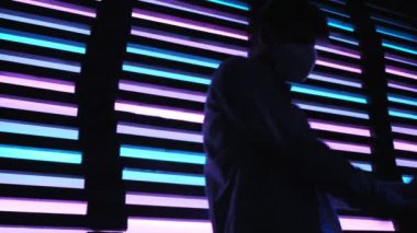 Koruyucu tıp maskeli yakışıklı adam neon gece kulübünde dans ediyor. çılgın parti