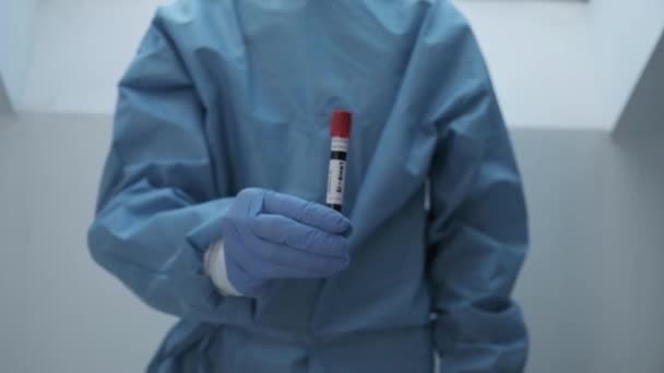 Microbiólogo, trabajador médico mano en guantes que muestran el resultado del análisis de sangre COVID-19 — Vídeo de stock