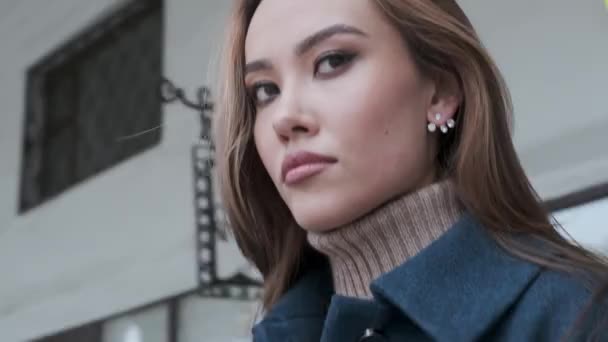 Close-up van stijlvolle gelukkig aziatisch mooi meisje in blauw jas en coltrui buiten — Stockvideo