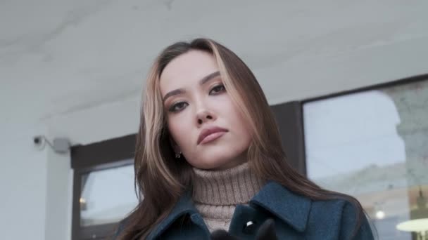 Nahaufnahme auf stilvolle lächelnde asiatische hübsche Mädchen in blauem Mantel, Rollkragen im Freien — Stockvideo