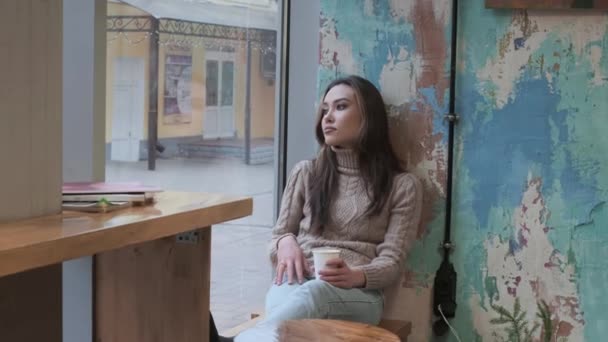 Elegante riflessivo giovane asiatica bella ragazza si siede al caffè, tiene la tazza di caffè — Video Stock