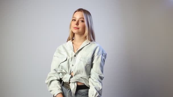 Joven caucásico bonita chica con largo pelo rubio, sonrisas sobre fondo blanco — Vídeos de Stock