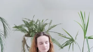 Spor kıyafetleri giyen bir kız Lotus pozisyonunda oturur gözleri kapalı, meditasyondan hoşlanır.
