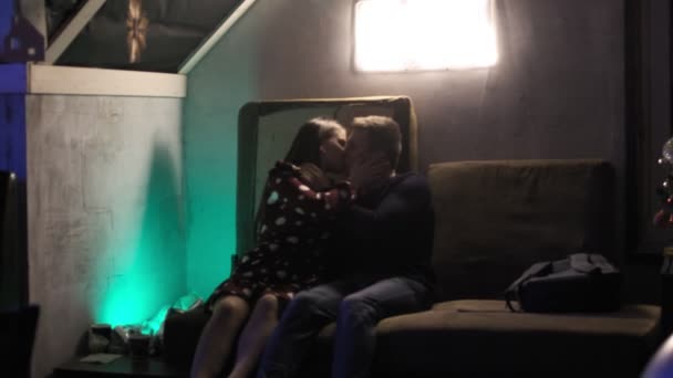 RUSSIA, VLADIMIR, 27 Aralık 2019: gece kulübünün karanlık odasında çift kanepede öpüşüyor — Stok video