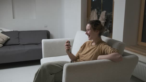 Mujer teniendo videocall en el teléfono inteligente. chica haciendo chat en línea en el teléfono en casa — Vídeo de stock