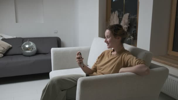 Женщина с видеокамерой на смартфоне. девушка ведет онлайн чат по телефону дома — стоковое видео