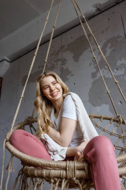 Evde kalıp, neşeyle vakit geçirmek. Güzel genç kız salıncakta sallanıyor